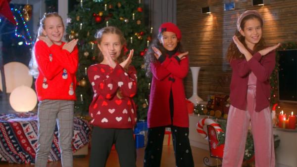 Viktoria, Nika, Laura und Sophia stehen vor einem geschmückten Weihnachtsbaum und singen ihren Weihnachtssong.