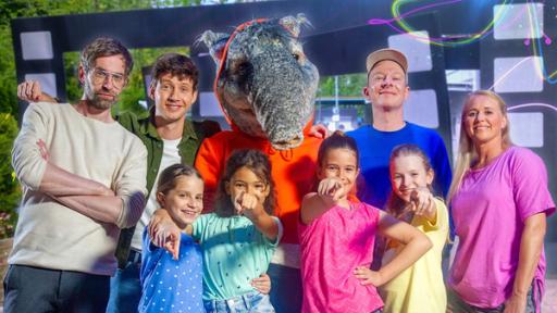 Rechte: KiKA/ZDF/Ron Bergmann Die Musiker "Deine Freunde", der TanzTapir, Moderatorin Singa und die TanzAlarm-Kids stehen vor dem Filmstudio.