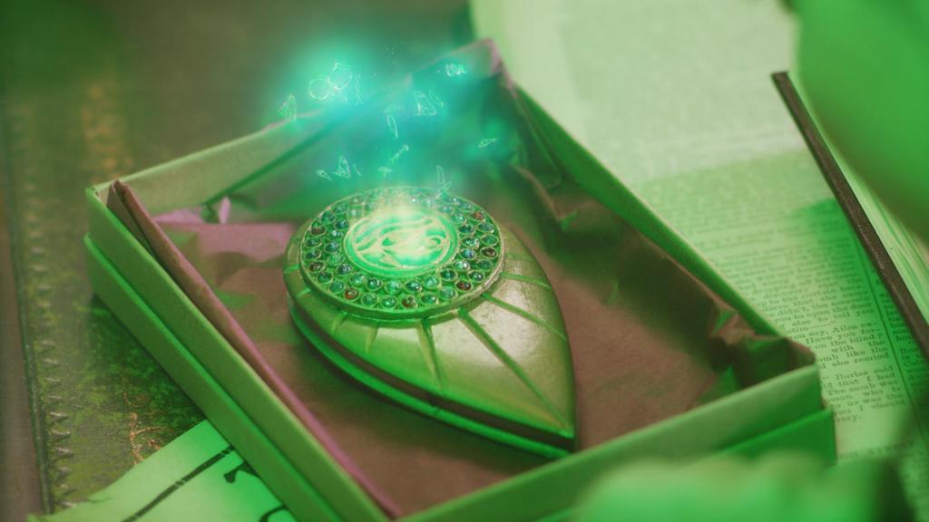 Vor Theodosia (Eloise Little) liegt ein Kästchen in dem sich ein amulettartiger Gegenstand aus Metall mit grün funkelndem Stein in der Mitte befindet.
