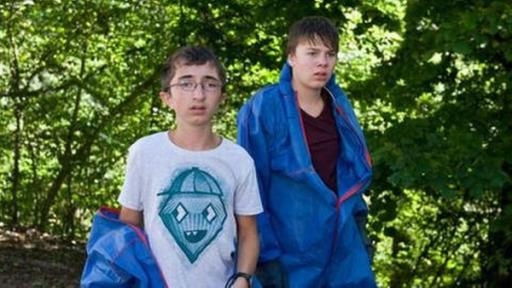 Zwei Jungs in Overalls stehen im Wald