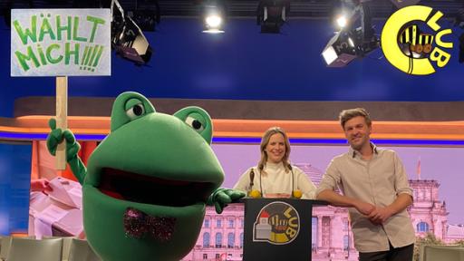 Günter Kastenfrosch mit Schild Wählt mich, daneben Linda von logo! und Tigerenten Club Moderator Johannes