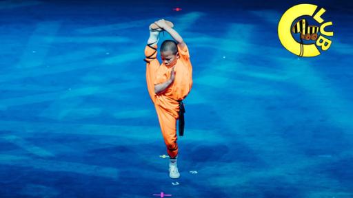 Shaolin-Schüler mit zum Spagat hochgestrecktem Bein in traditioneller Tracht