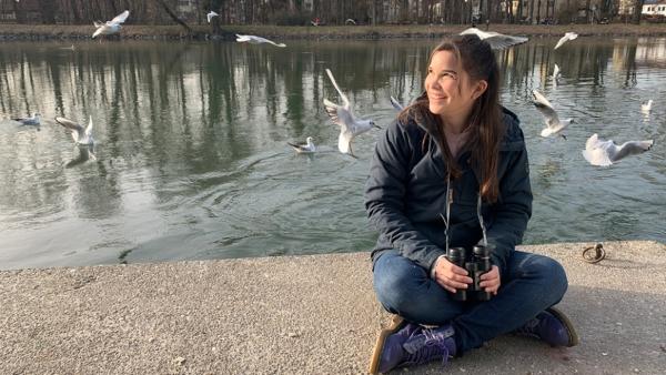 Wie lacht die Lachmöwe? | Anna sitzt an der Isar und beobachtet Lachmöwen mit dem Fernglas. | Bild: BR | Text und Bild Medienproduktion GmbH & Co. KG