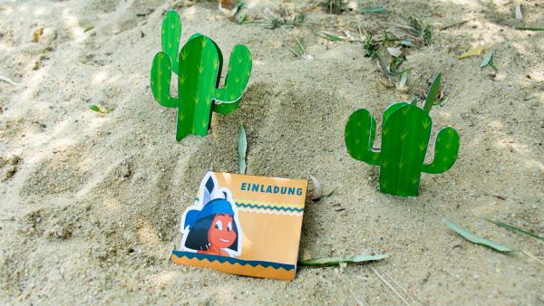 Eine Yakari - Geburtstagseinladungskarte steht mit Kakteen im Sand.