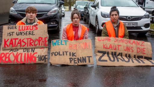 Young Crime - Teaser - Staffel 3 - Klimakleber vor Gericht | Rechte: ZDF Drei Jugendliche sitzen auf einer Straße, sie tragen Warnwesten und Protestschilder